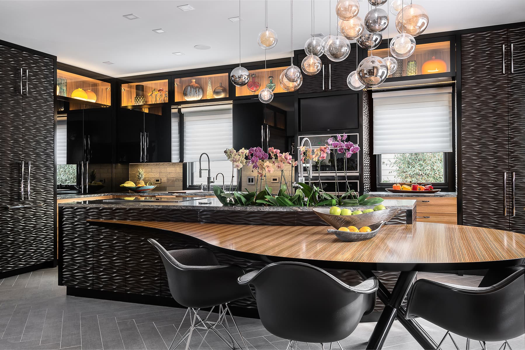 Luxury kitchen with large wood island, black cabinetry, sculptural glass pendant lighting, and modern seating in a high-end residential design